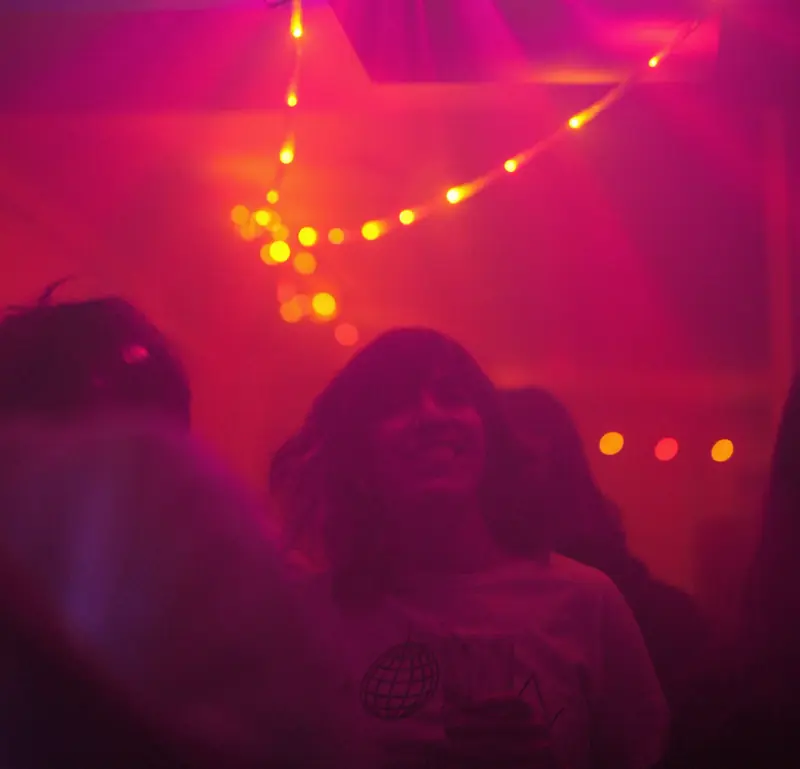 Une soirée au Bistro Sauvage sous une guirlande de lumières, dans une lumière rose et rouge.