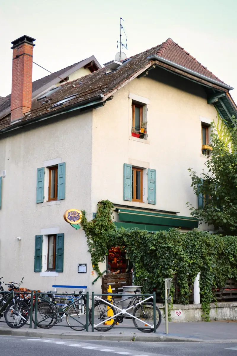 La maison du Bistro Sauvage : façade claire aux volets bleus, vigne vierge sur la terrasse, vélos garés devant.